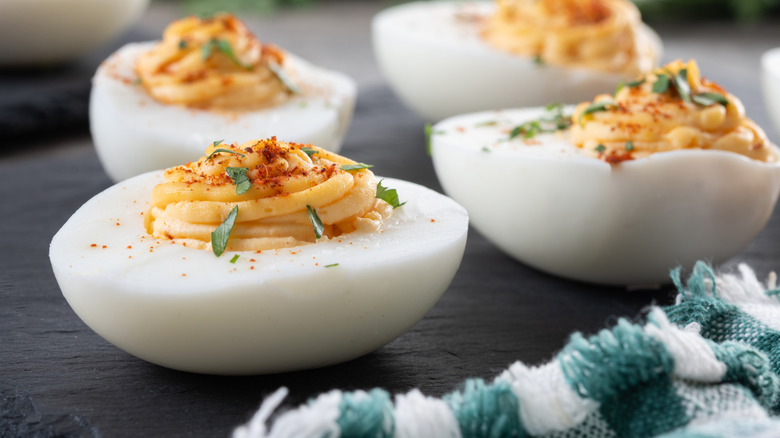 Plate of deviled eggs with paprika and herbs.