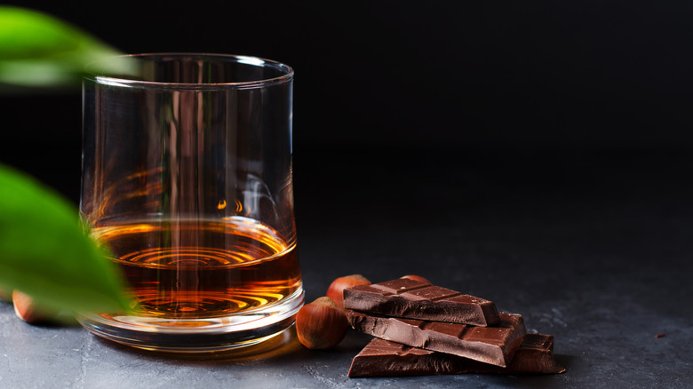 a glass of bourbon next to chocolate
