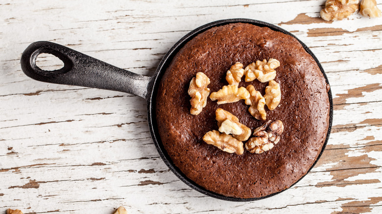 Brownies baked in a cast iron pan with walnuts on top.