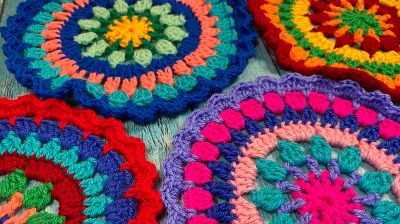 Multicolored crocheted doilies on blue wood background.