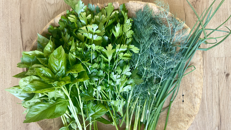 basil, parsley, dill and chives on a wooden cutting board