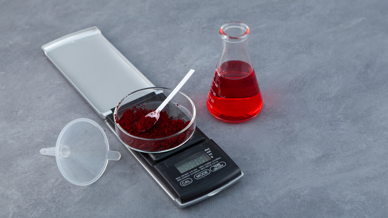 Glass beaker and dish containing red food dye in powdered and liquid forms