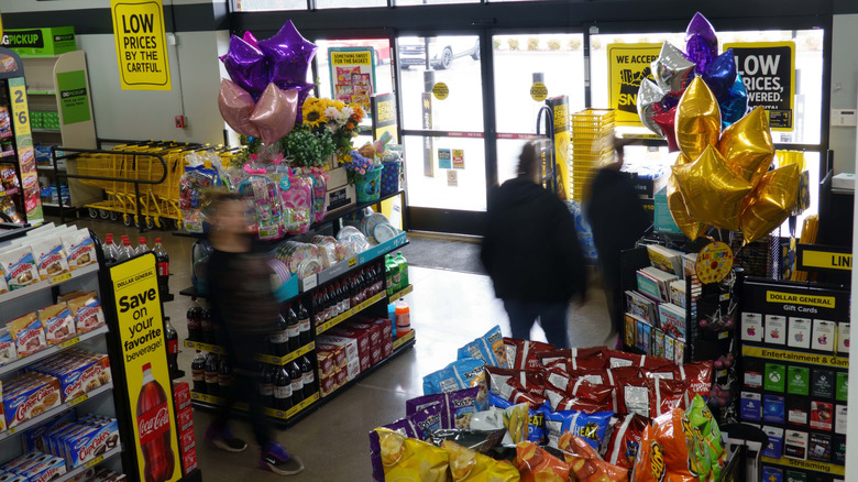 The inside of a Dollar General store with people walking toward the door.