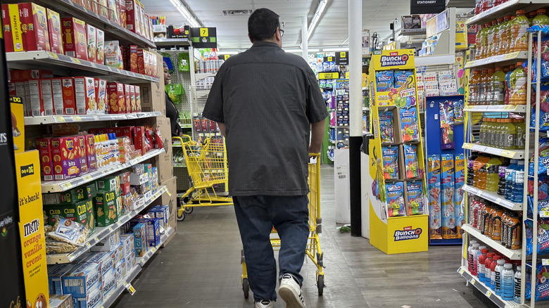 A man pushes a shopping cart in a Dollar General.