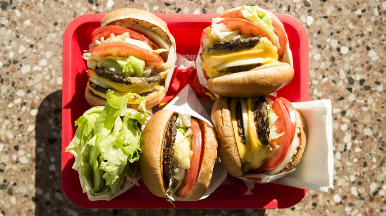 Fast food burgers in paper wrappers on a red tray