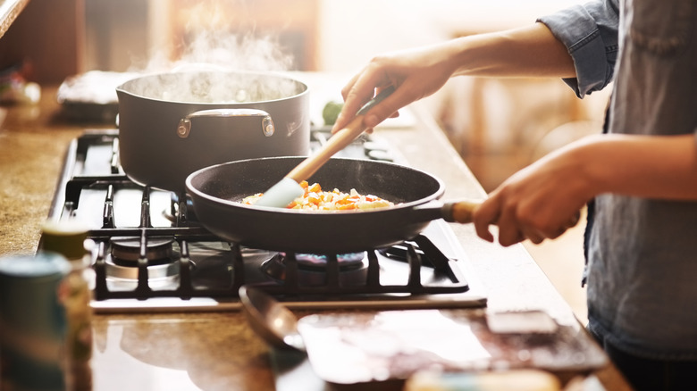 caucasian hands cooking food on gas stovetop