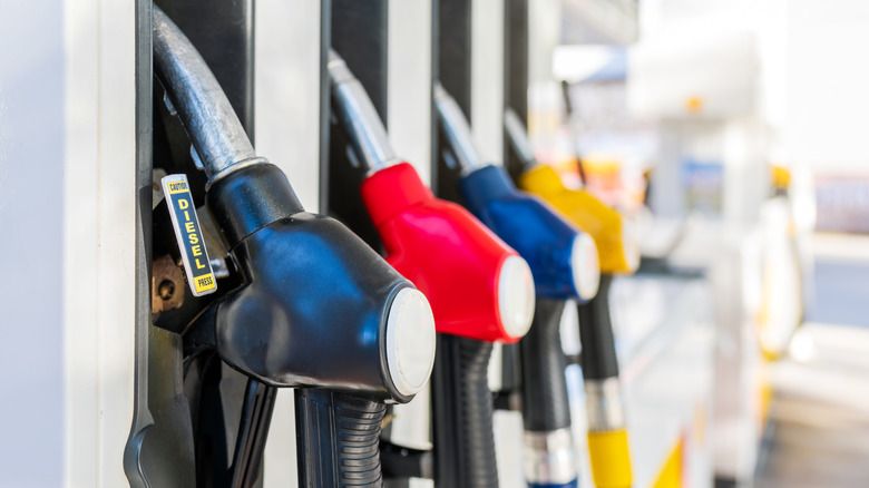 Several colored fuel pumps at a gas station lined up next to each other