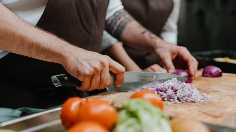 Chef's hands slicing vegetables