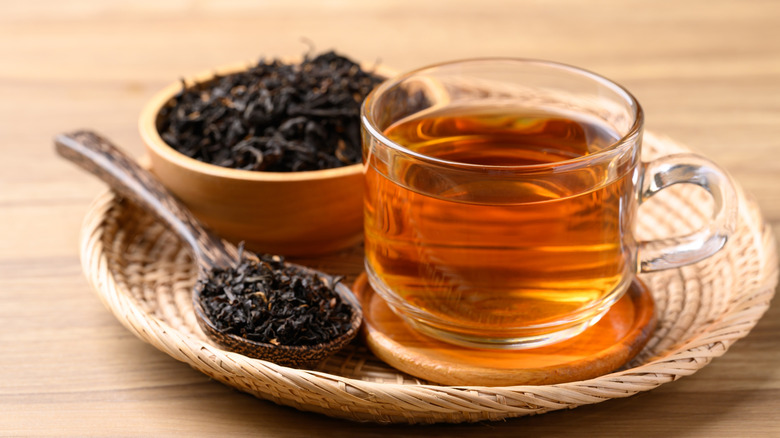 A glass of herbal tea and a spoonful of loose-leaf tea.