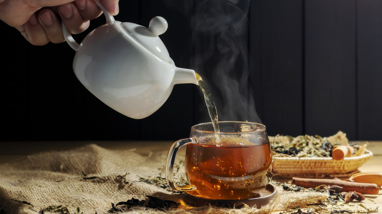 Tea pouring from a pot into a glass tea cup.