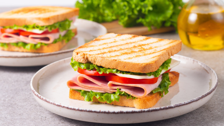 Two hearty sandwiches where the meat has been folded for volume are on white plates.