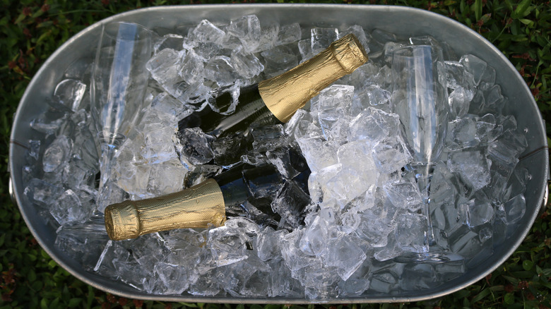 Two bottles of Champagne are situated in a metal tub of ice.