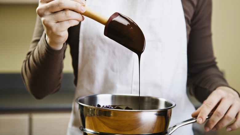 Drizzling chocolate into a mixing bowl
