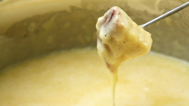 Close-up of cheese fondue dripping from a metal skewer