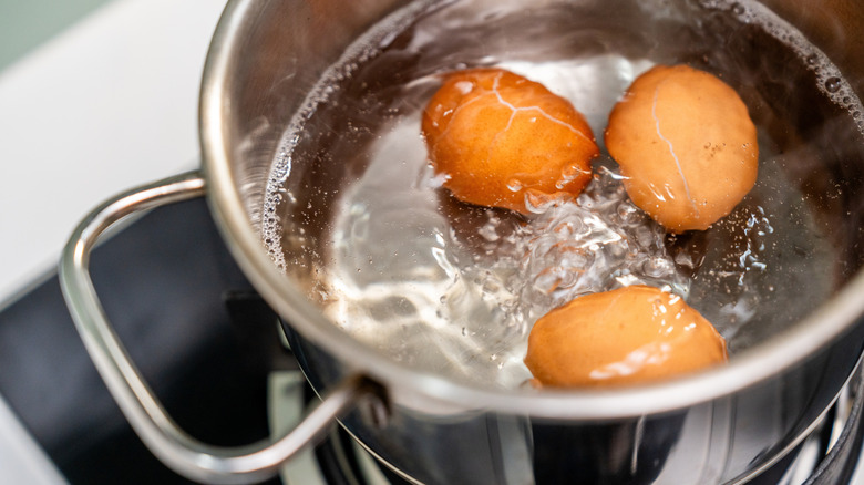 Three boiling eggs in a saucepan