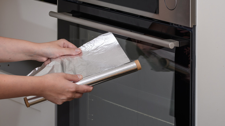 Hands unrolling aluminum foil in the kitchen