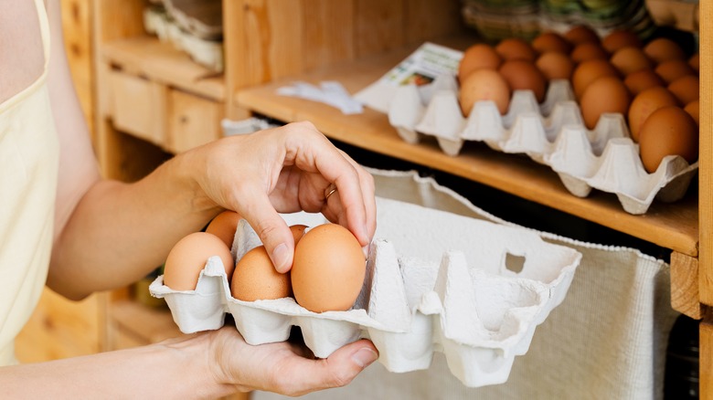 person going through eggs in a carton