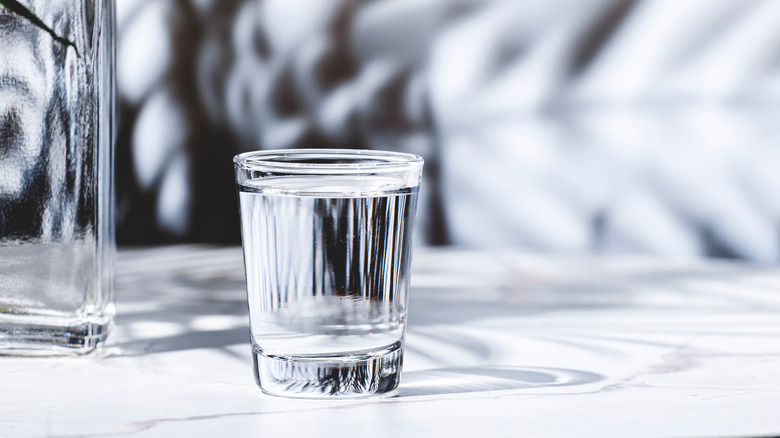 Shot glass of vodka on a white table