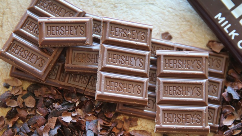 The contents of a bar of Hershey's chocolate with a wrapper off to the side