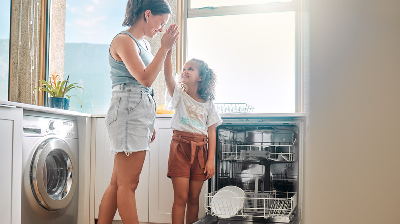 Mom and daughter high-fiving while unloading dishwasher