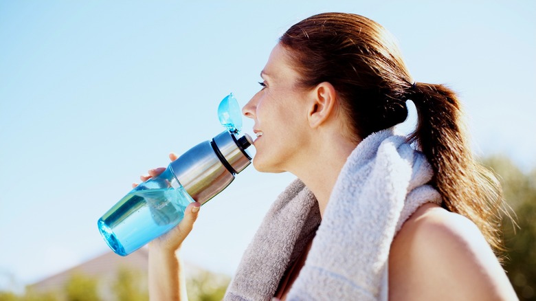 woman drinking water after jogging