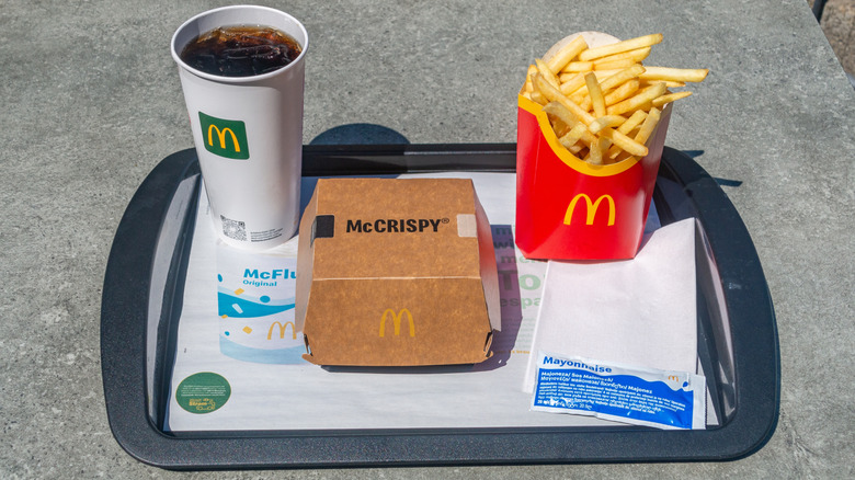 A McDonald's tray with a packet of mayonnaise, a fountain drink, fries, and a McCrispy sandwich