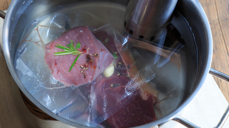 Sealed cuts of meat being cooked in a sous vide bath