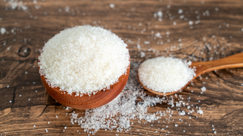 White table sugar in wooden bowl and wooden spoon.