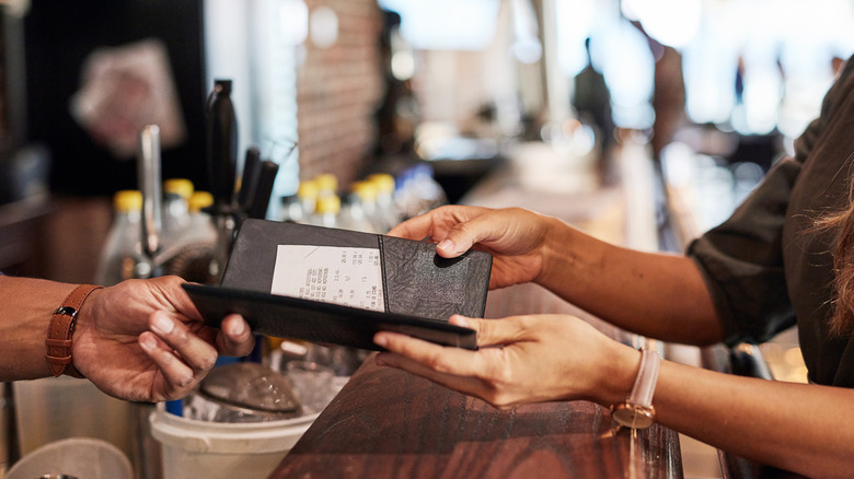 Person paying a restaurant bill at a bar
