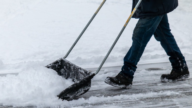 A person shoveling snow off a driveway or sidewalk.