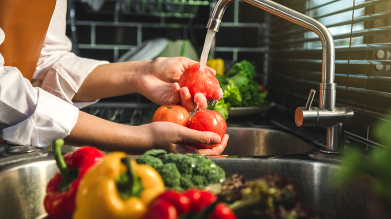 A woman washing fresh produce in the sink