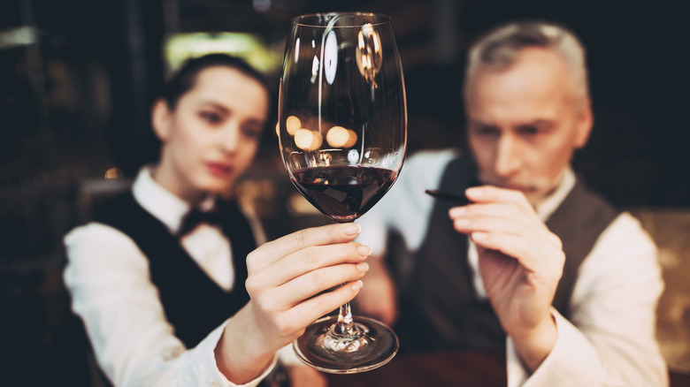 Two sommeliers analyzing a glass of wine