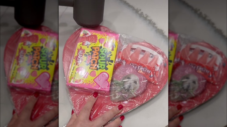 Heart shaped sign with Valentine's candy, with a blowdryer being used to shrink wrap the package
