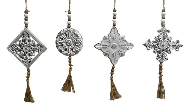 A product image of the Beaded Wood Tassel Hanger, showing four different variations, all of which have intricate carvings.