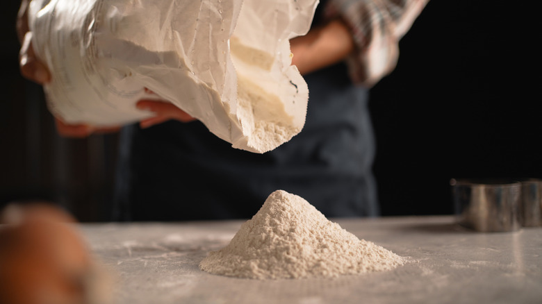 Person pouring flour onto a table