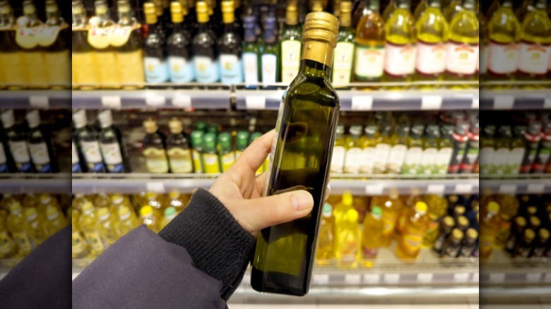 Hand holding a bottle of vegetable oil in a grocery store aisle