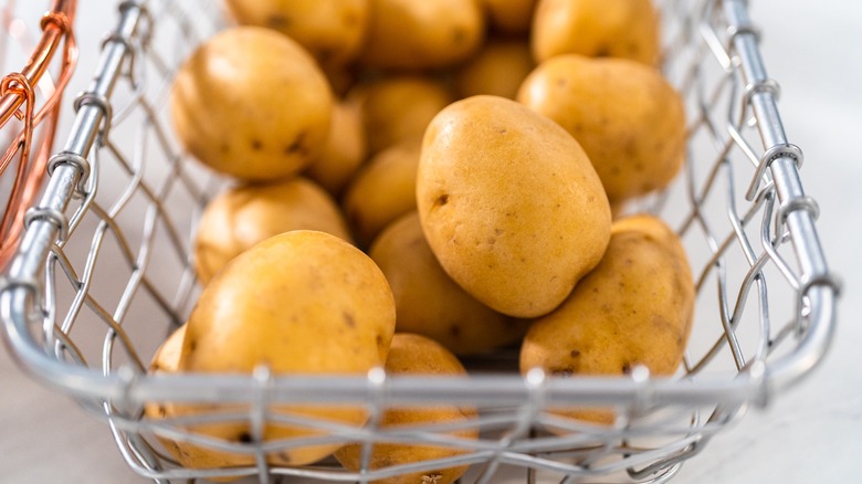 Raw potatoes stored in a silver wire basket