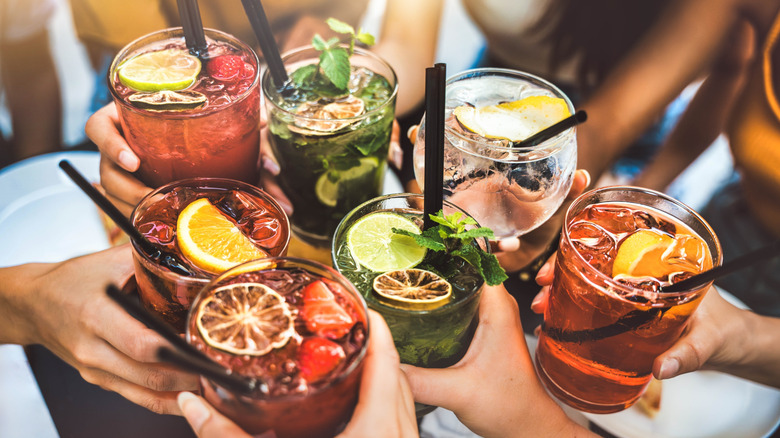 hands toasting colorful cocktails