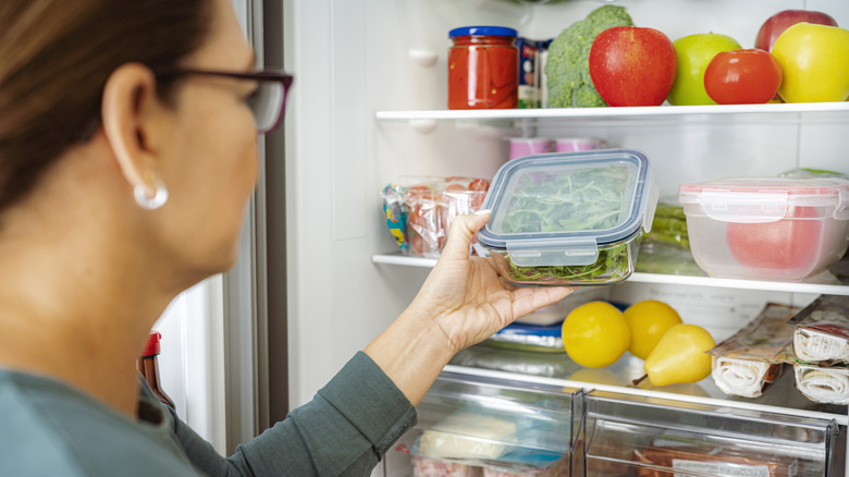 Woman pulling out food from an organized refrigerator