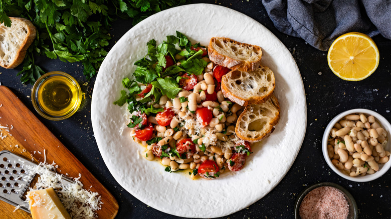 a bean salad plated with bread and green leaves on the side