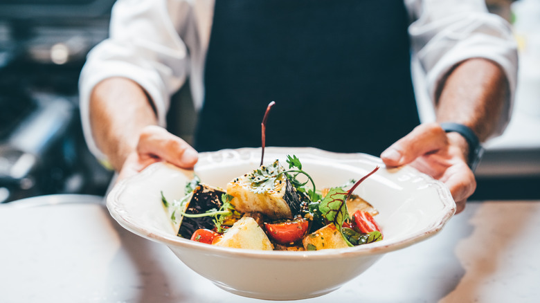 Chef presenting bowl of finished seafood dish