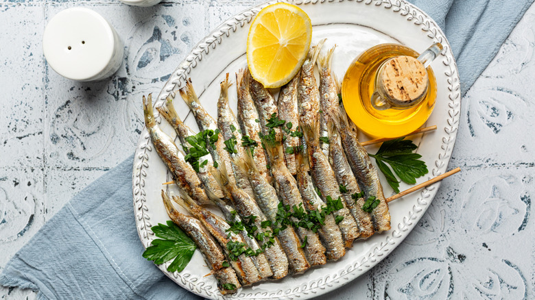 grilled sardines on a plate with lemon and oil
