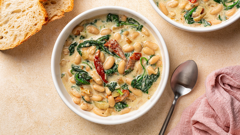 Bowls containing Tuscan butter beans stew with spinach and sun-dried tomato.