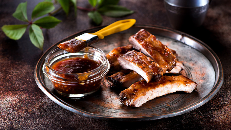 Baby back ribs on a plate with sauce.