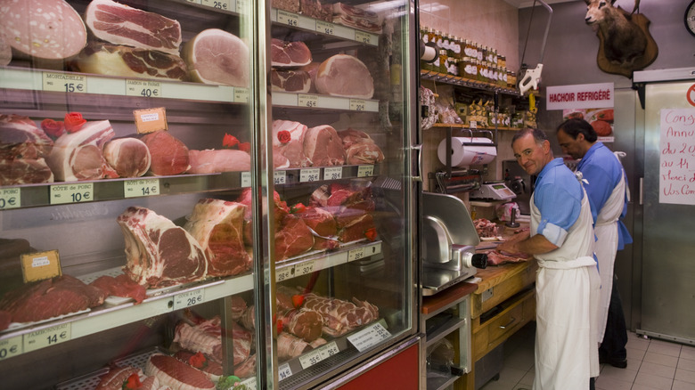 Butchers work in the backroom of a butcher shop