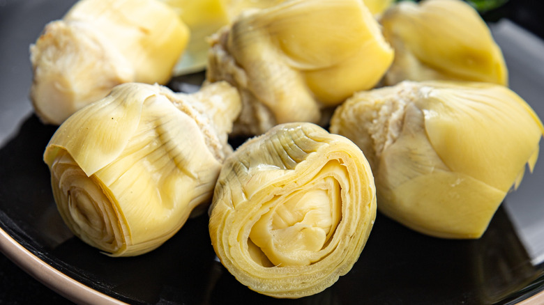 Canned artichoke hearts have been removed to a plate.