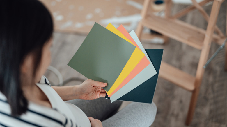 A person is seen from over the shoulder viewing paint swatches.