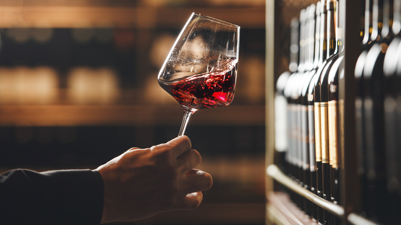 A glass of red wine being swirled and evaluated by a sommelier.