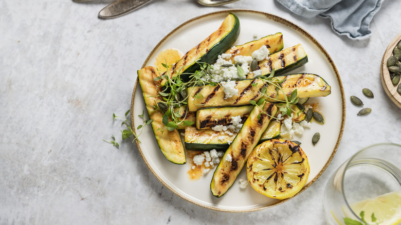 grilled zucchini and lemon on a plate with cheese on a white background