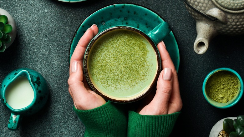 Woman wrapping hands around a mug of matcha tea